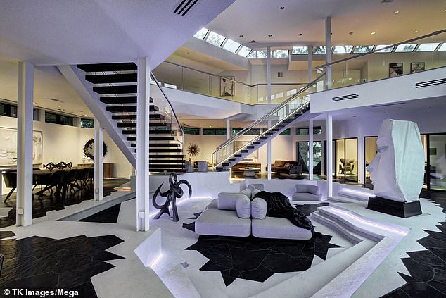 It features two large floating glass staircases, overlooking a sunken living room and floor-to-ceiling windows