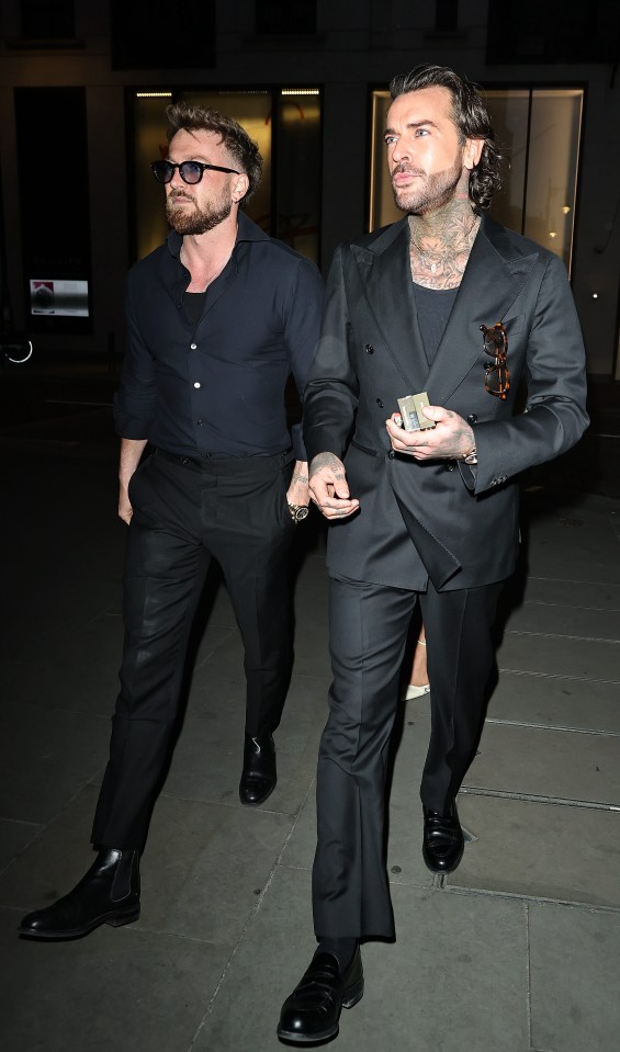 Two men in black suits walking at night.