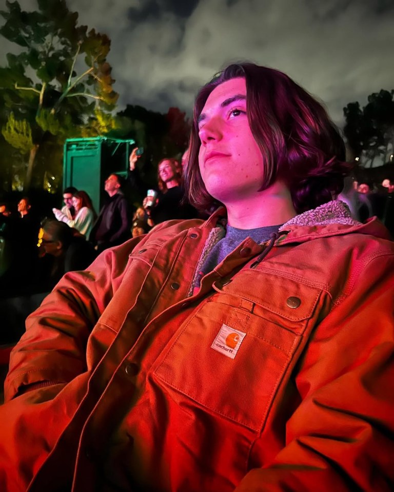 Person in an orange jacket at an outdoor event.