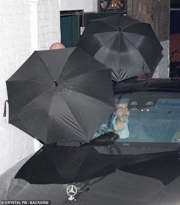 The couple made an effort to hide their relationship as they left the venue shielded by umbrellas