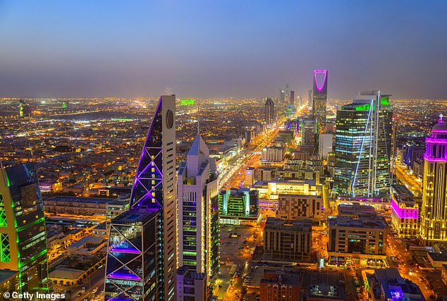 An elevated view shows the bright lights of Riyadh as the sun sets in the dessert city