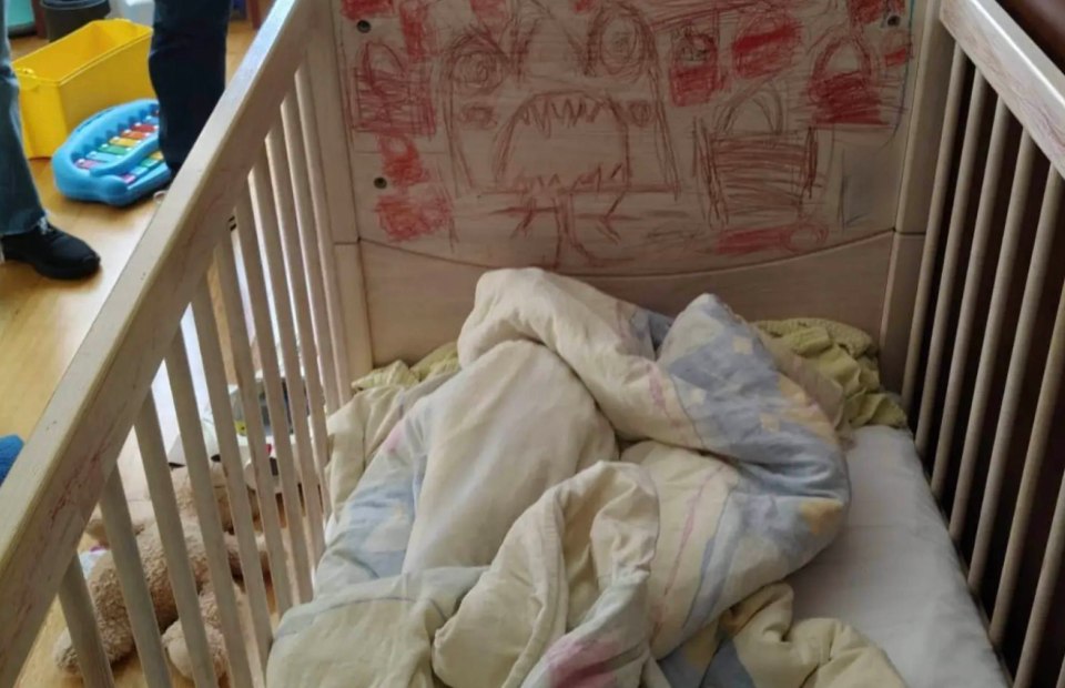Child's crib with crayon drawings and bedding.