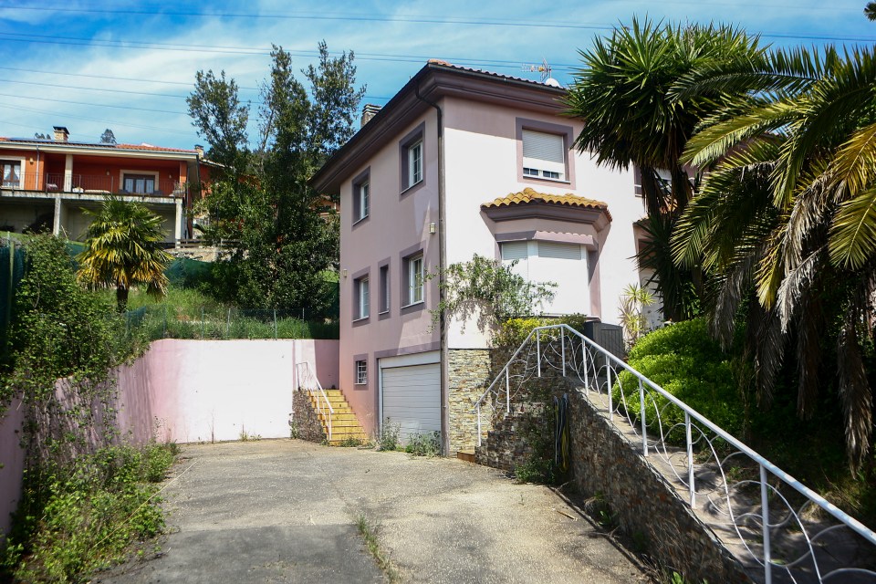 Pink house with a garage and stairs leading up to the entrance.