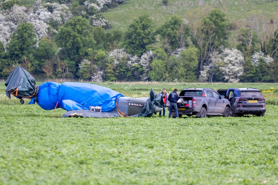 Volunteers guarding a crash-landed 1940s Spitfire in a field.