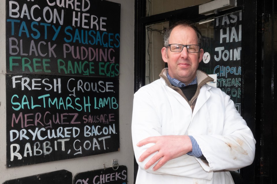 Butcher standing outside his shop.