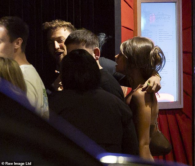 He had his arm around her shoulders as they stood chatting to pals