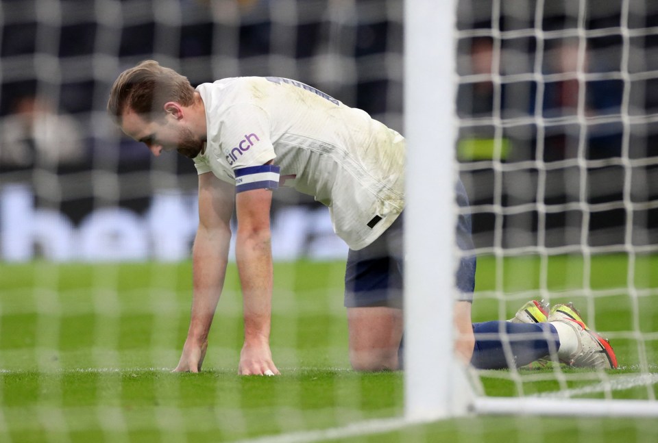 Harry Kane kneeling on the field near the goal.