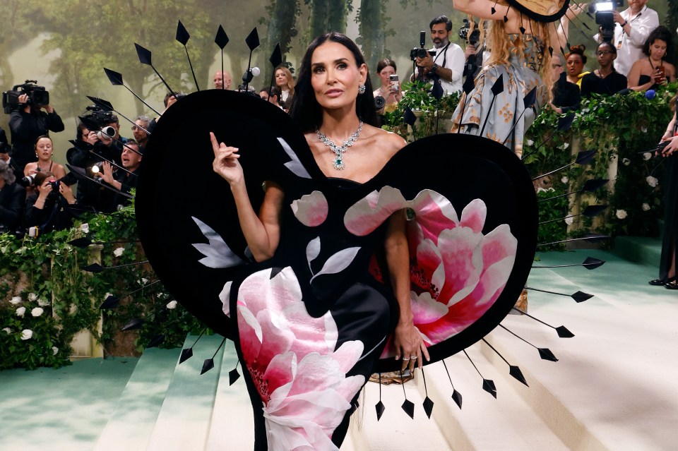 Demi Moore at the Met Gala wearing a black and pink floral gown.