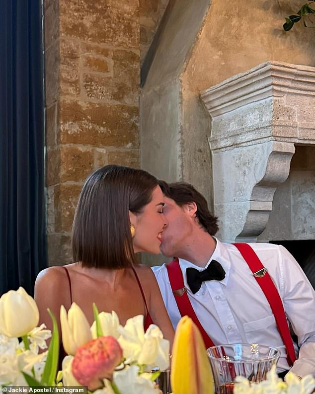 The loved-up couple shared kisses at the flower-adorned dinner table, with Cruz matching his girlfriend's red gown with his red braces