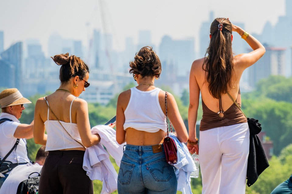 Three women enjoying a sunny day, overlooking a city skyline.