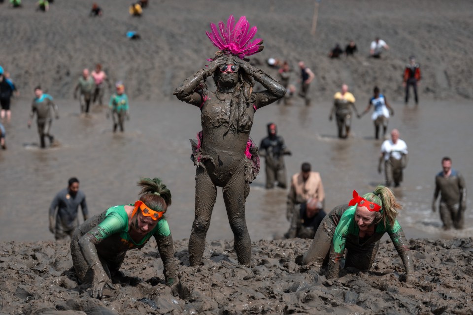 Competitors covered in mud participate in a mud race.