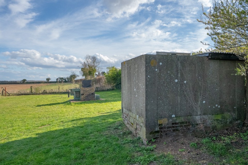 Two concrete structures in a grassy field.
