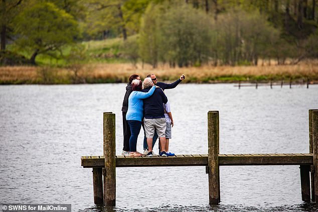 A group of tourists squeeze in for a selfie on the edge of Ambleside Pier in the Lake District