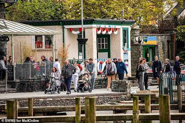 Tourists make their way along the water's edge in Ambleside. Locals say trying to navigate the roads is a 'nightmare' at the peak of the season