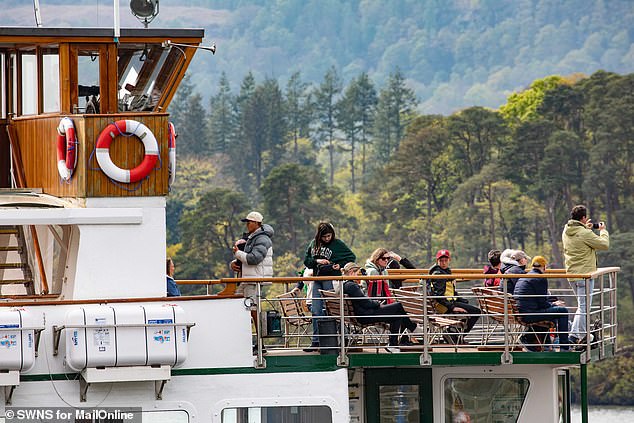 Tourists ahoy! Visitors survey the scene as their boat cruises by Ambleside - boosting the economy and annoying locals in one swoop