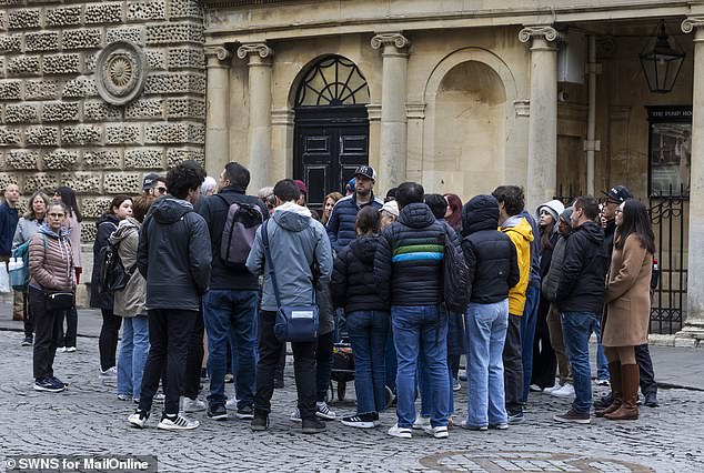 A large group of tourists gathered outside the entrance to the Roman Baths museum
