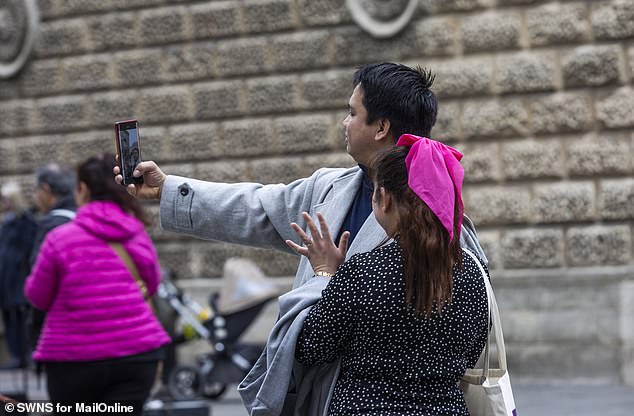 Tourists snap a selfie outside the Roman Baths on a visit to Bath