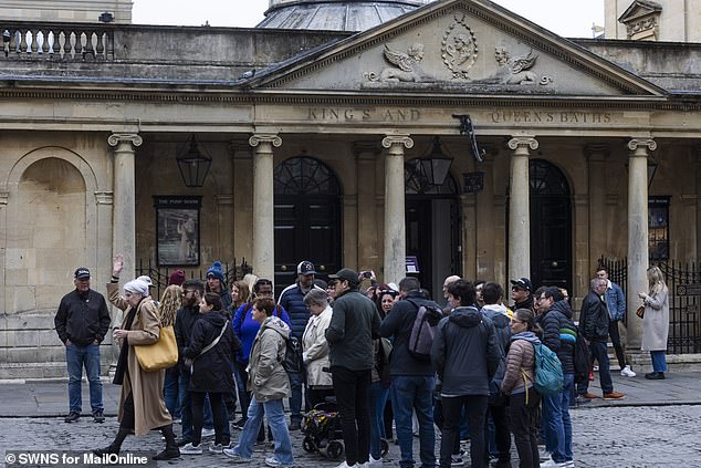 A tourist group is led past the Roman Baths by a tour guide. While tourism is seen as crucial to the economy, some residents worry about the impact on the city as a whole