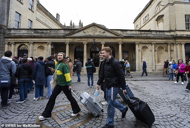 Tourists drag their suitcases past the entrance to the Roman Baths in the centre of the Somerset city