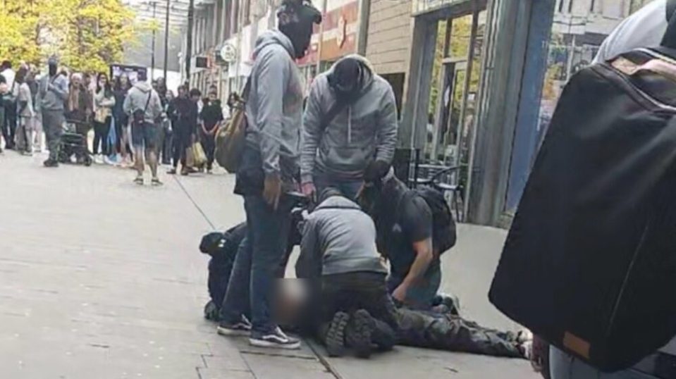 Several people restraining a person on the ground.