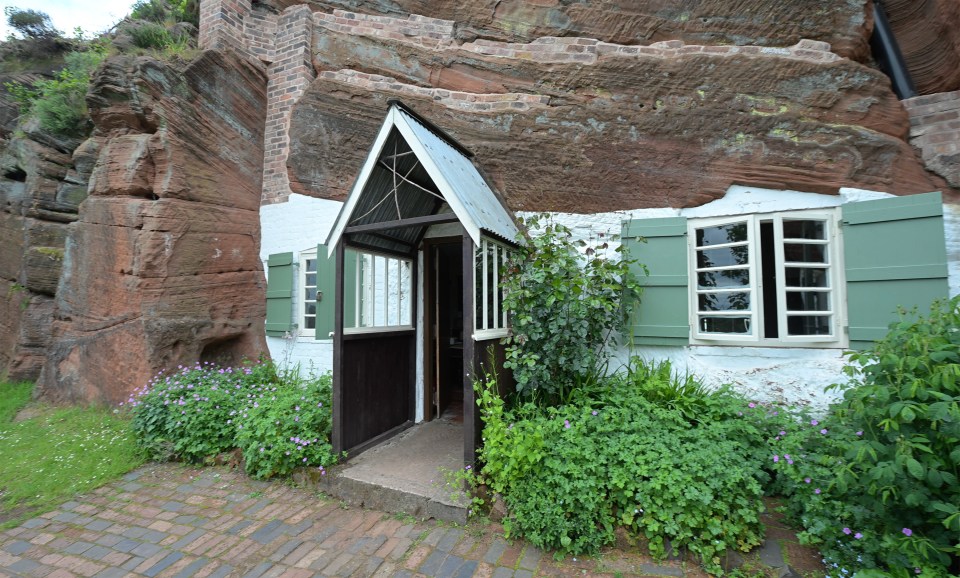 A rock house with a small front door and green shutters.