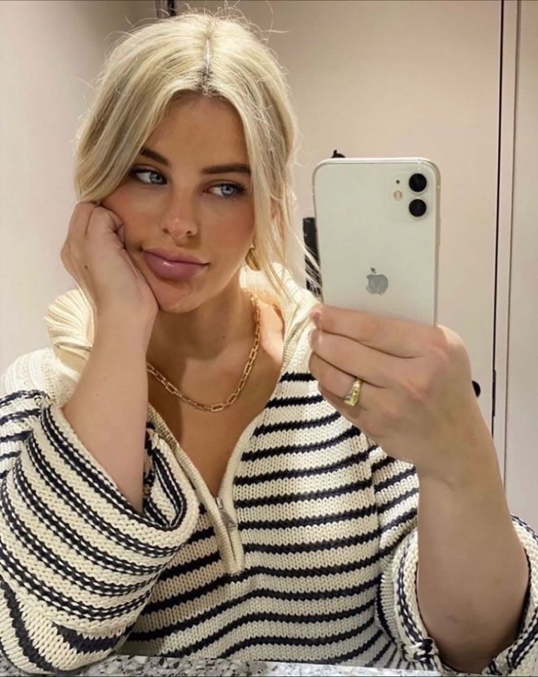 Selfie of a blonde woman wearing a striped sweater.