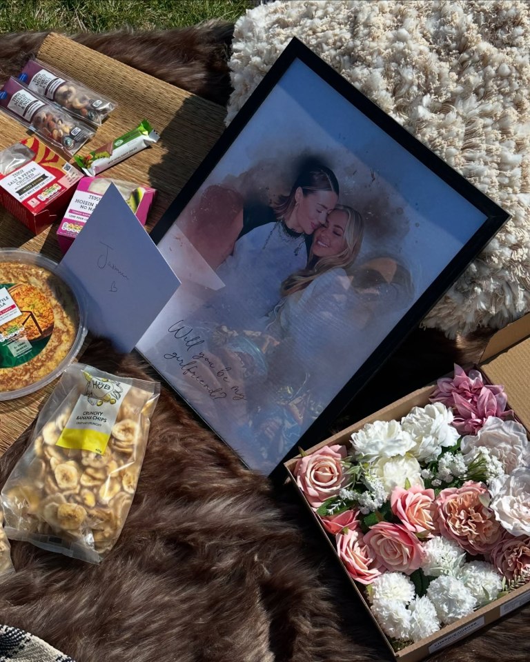 Girlfriend proposal scene with framed photo, snacks, and flowers.