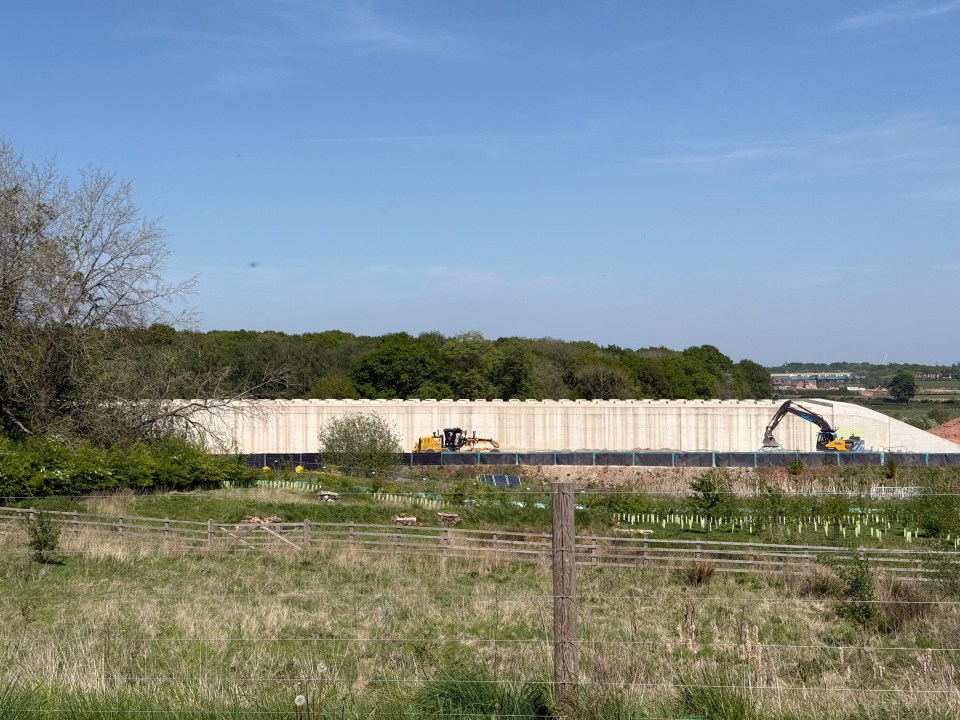 HS2 construction site with large concrete wall and machinery.