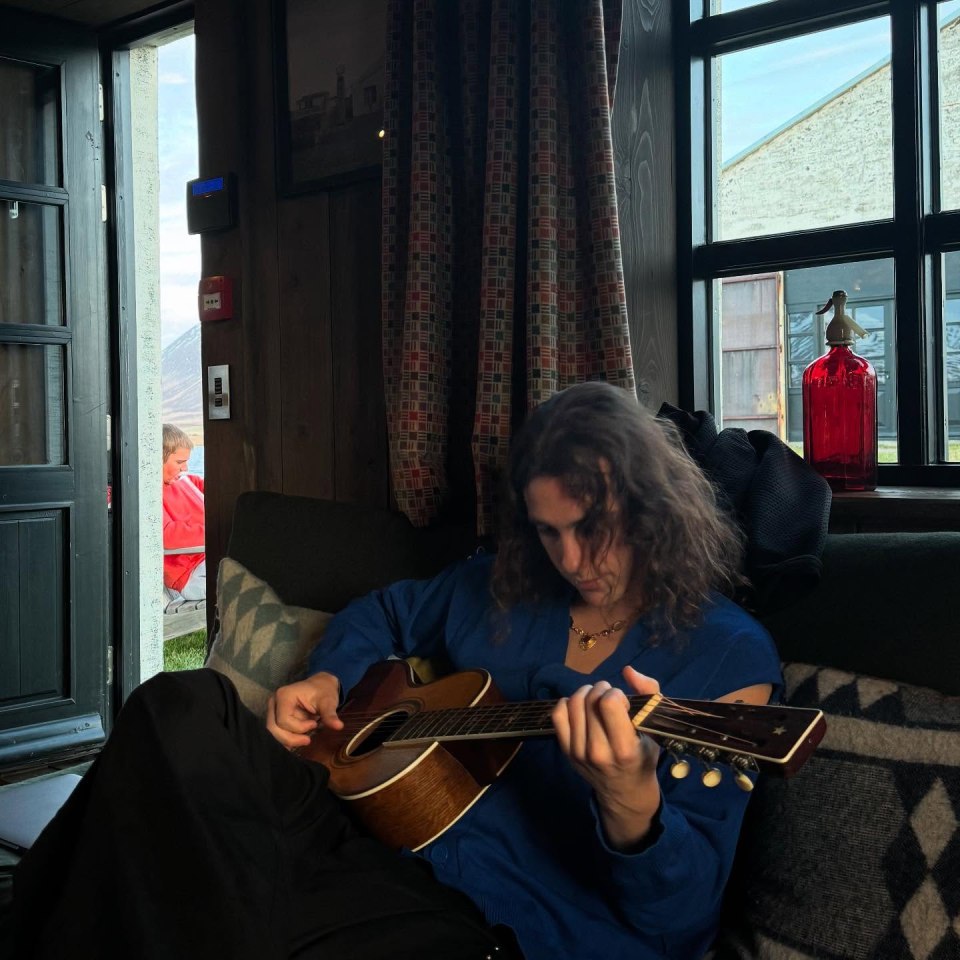 Person playing acoustic guitar indoors.