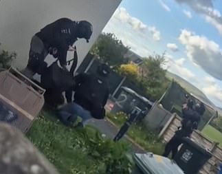 Officers are seen detaining one suspect while another officer covers the window of a building
