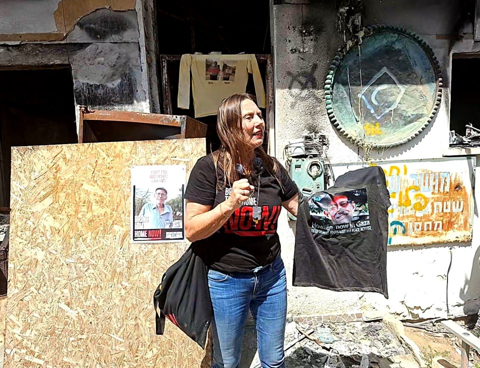 Woman holding a shirt with a photo of a hostage and a missing person poster.