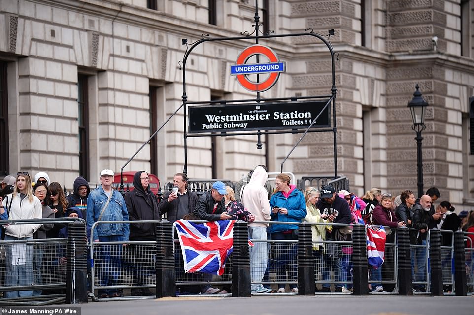 Members of the public wait near Parliament Square in London today ahead of a procession for the 80th anniversary of VE Day