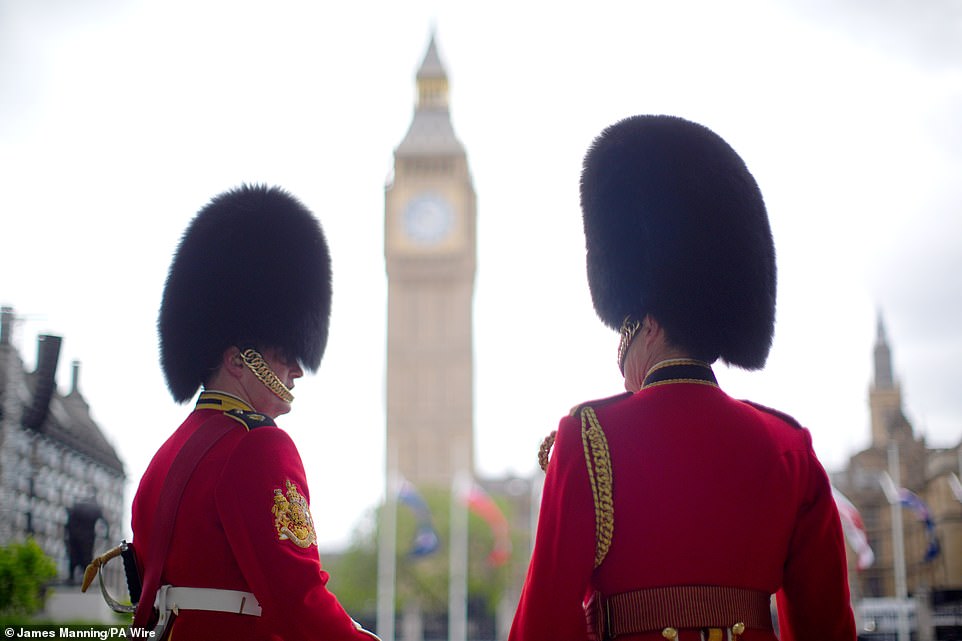Members of the Household Division stand near Parliament Square in London today ahead of the military procession