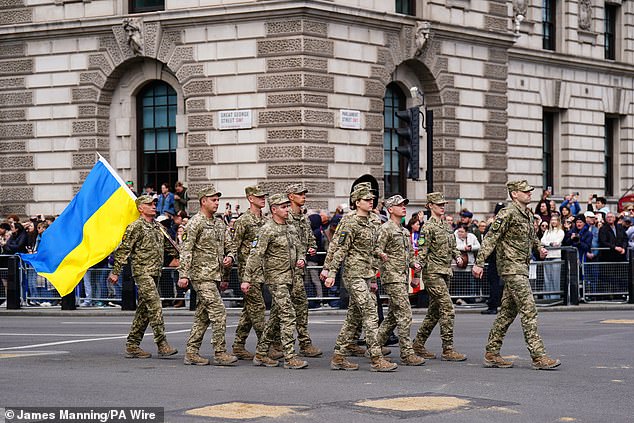 Members of the Ukrainian military march past Parliament Square in London today ahead of the military procession