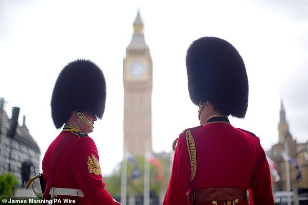 Members of the Household Division stand near Parliament Square in London today ahead of the military procession