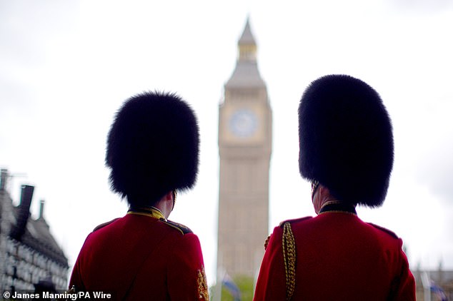 Members of the Household Division stand near Parliament Square in London today ahead of the military procession
