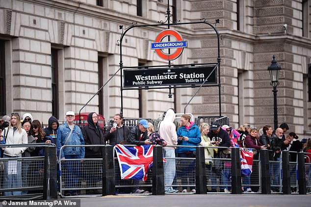 Members of the public wait near Parliament Square in London today ahead of a procession for the 80th anniversary of VE Day