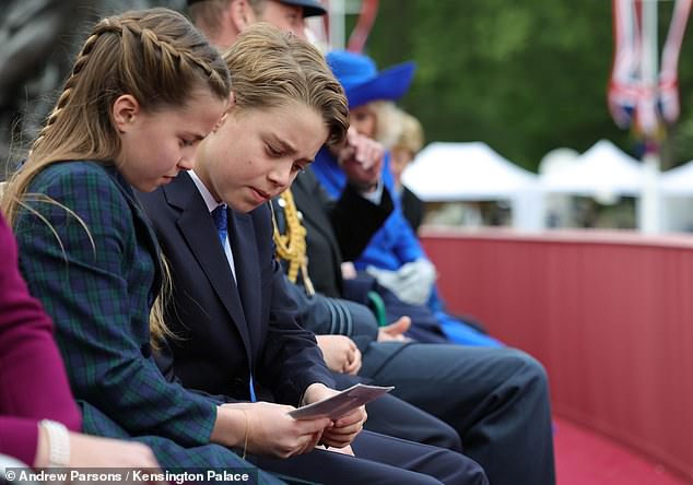 Princess Charlotte then sweetly followed her mother's lead as she looked over the photos with Prince George, as Prince Louis (not pictured) remained engrossed in the parad