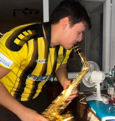 Person in a yellow and black jersey playing a saxophone.