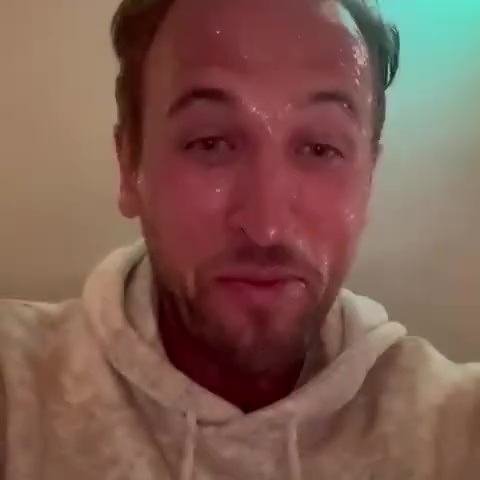 Harry Kane, sweaty and smiling, wearing a light-colored hoodie.