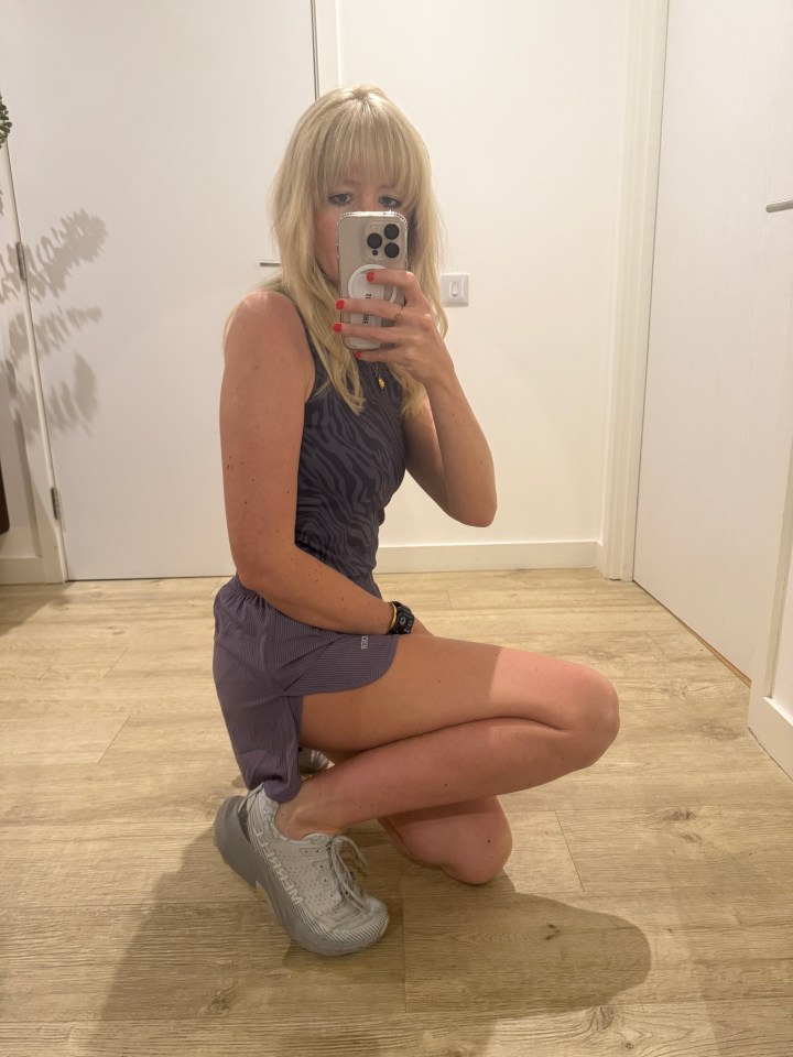 Woman taking a selfie in a purple athletic outfit and gray sneakers.