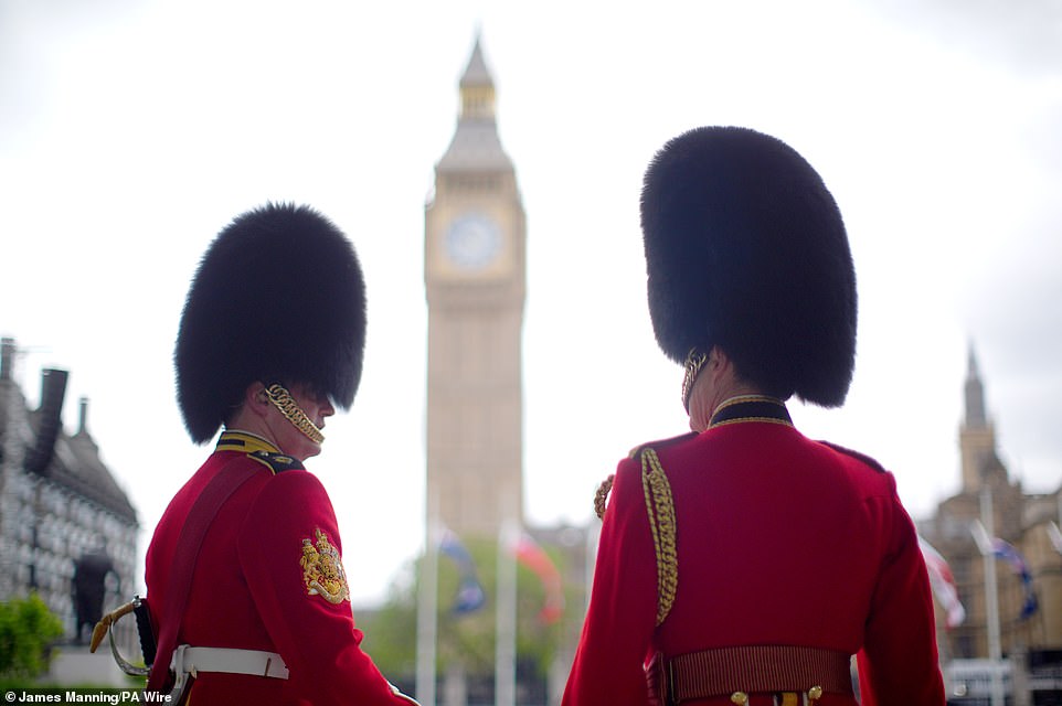 Members of the Household Division stand near Parliament Square in London today ahead of the military procession