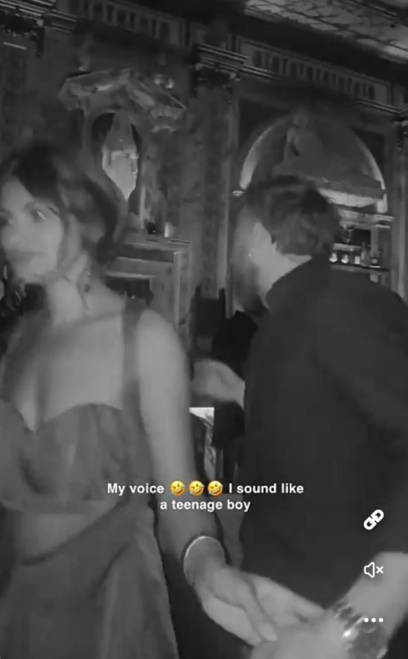 Screenshot of a black and white video showing two people holding hands in a dimly lit bar.