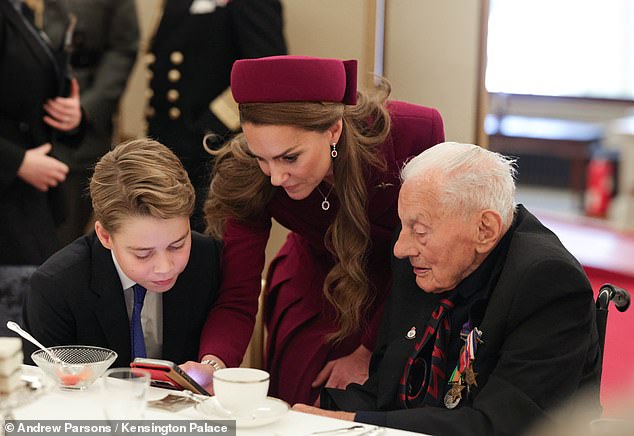 The Princess appeared to show George and a veteran in attendance something on her phone at the party