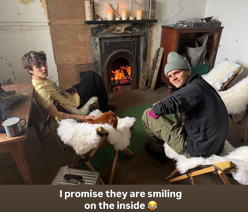 Cruz and Romeo Beckham sitting by a fireplace.