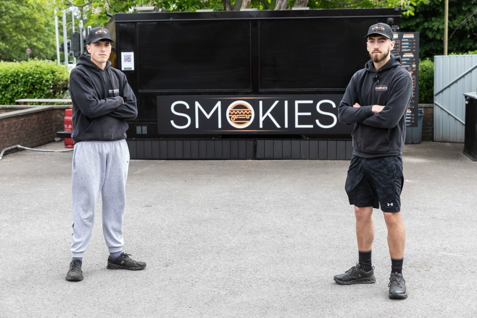 Two men stand in front of their "Smokies" smash burger van.