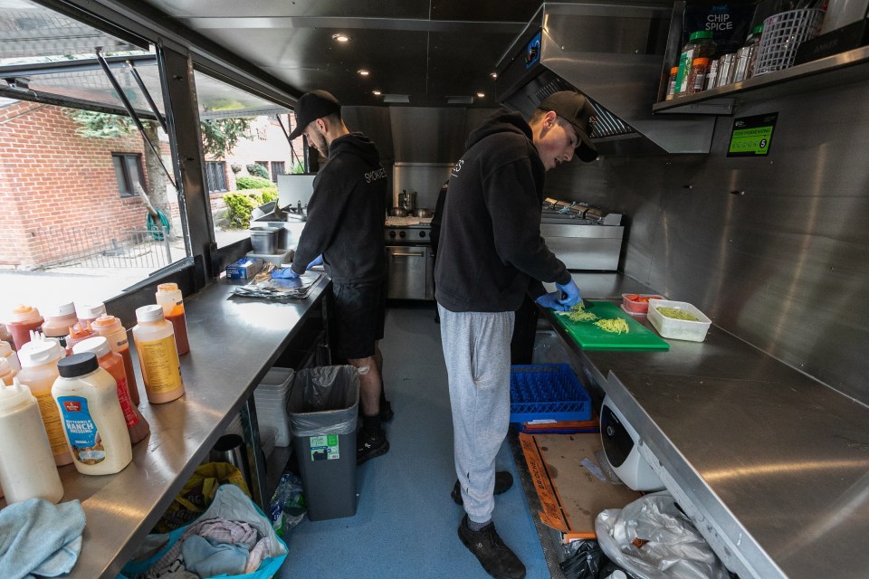 Two people preparing food inside a food truck.