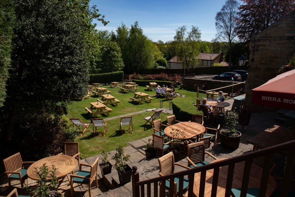 Outdoor patio area of a pub with picnic tables and seating.