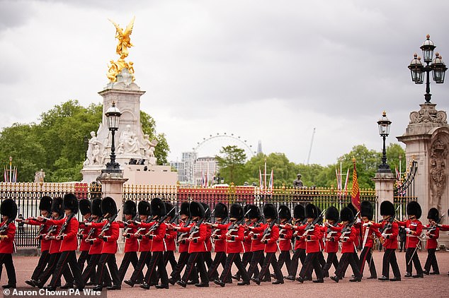 Grenadier Guards march past the Queen Victoria Memorial during a military procession along The Mall this afternoon