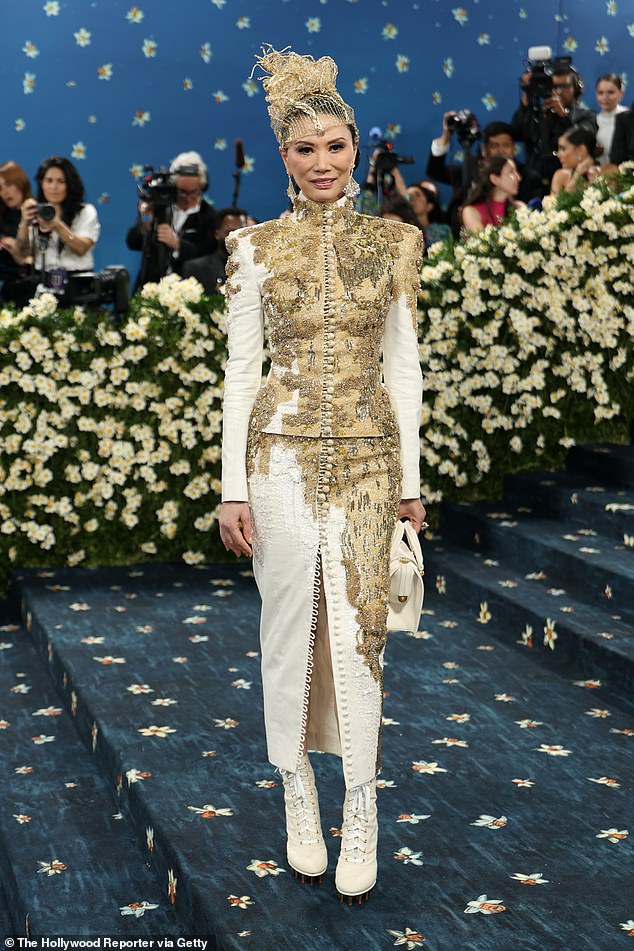 A lot going on! Entrepreneur Wendi Murdoch showed up to the Met Gala steps in a matching, two-piece suit set custom made by Thom Browne that featured gold detailing on the jacket and skirt. On her feet, she wore dramatic, white leather lace-up boots and a gold hat that almost looked like it was mad from wire